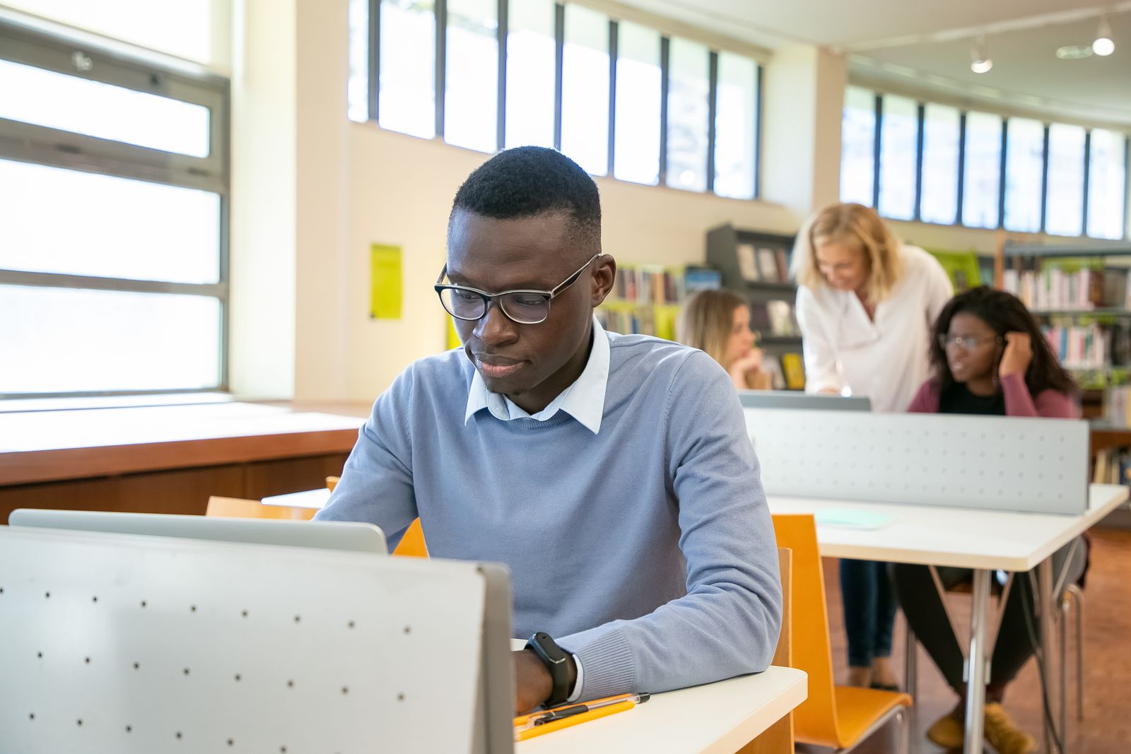 Un étudiant travaille sur ordinateur dans une bibliothèque universitaire